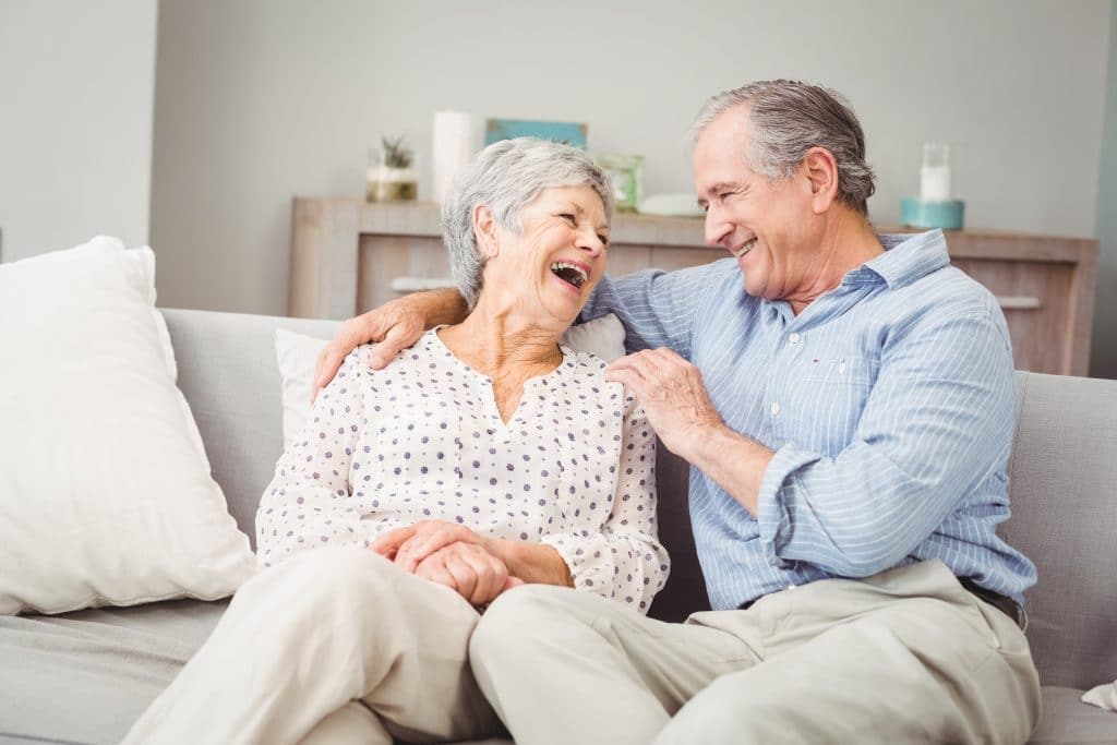 senior couple laughing on couch