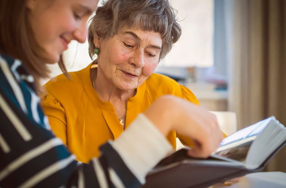 Senior woman and adult daughter look through scrapbook together