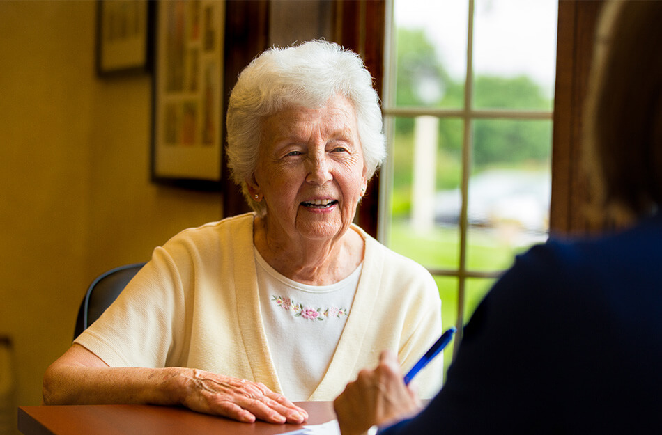 Senior woman sitting with another woman and paperwork