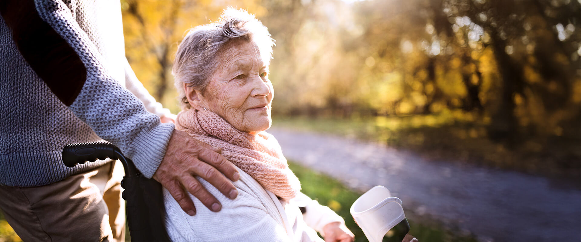 Elderly woman in wheelchair on a stroll with man