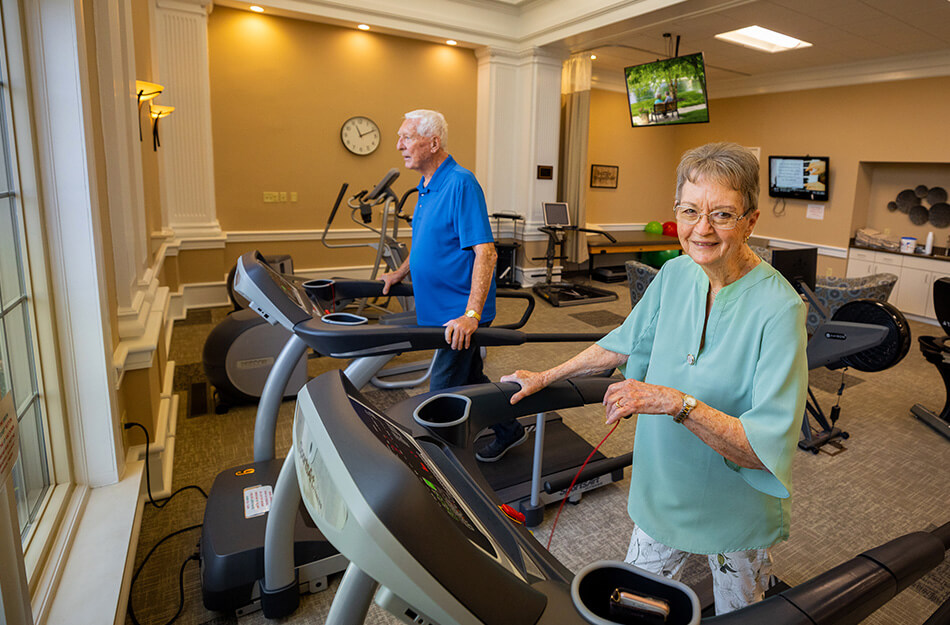Seniors walk on treadmill in exercise room