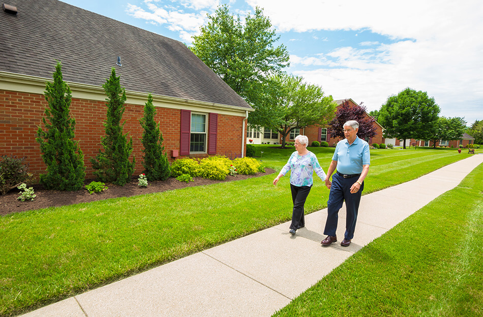 senior couple walks on path through the neighborhood