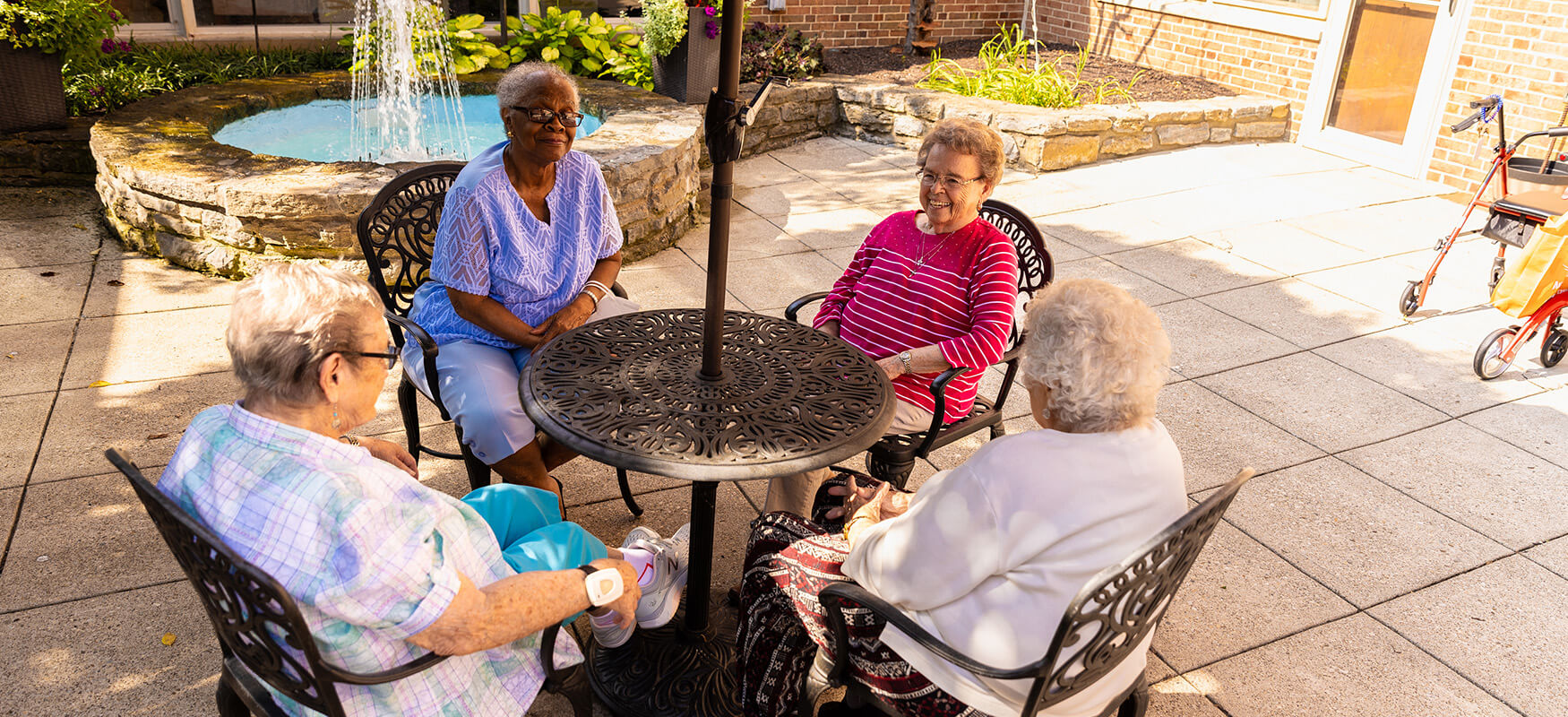 Senior friends sit around a table in the shade