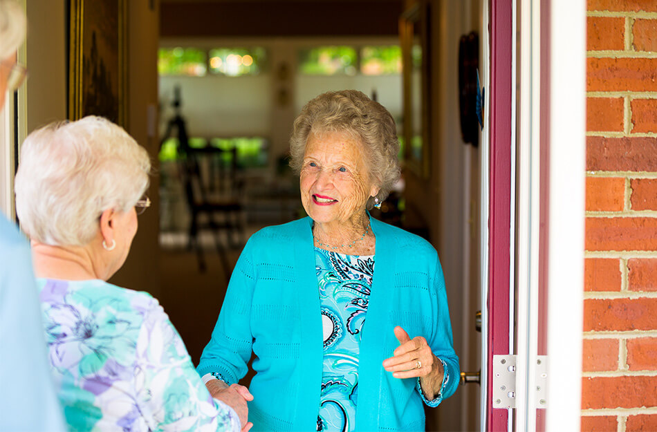 Senior friends talk at the doorway