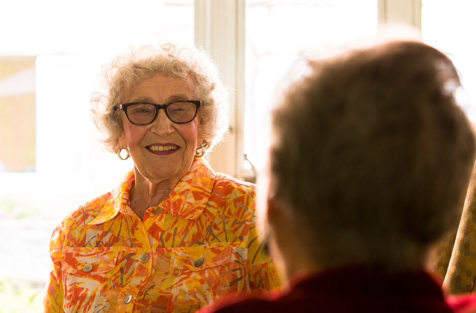 Senior woman smiling while sitting with another senior woman