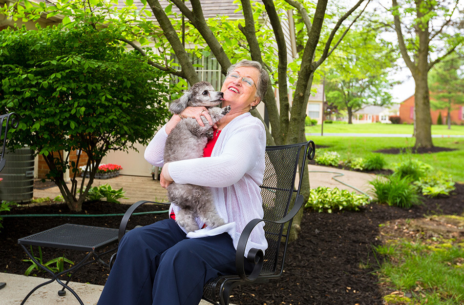 Senior woman hugging dog outside