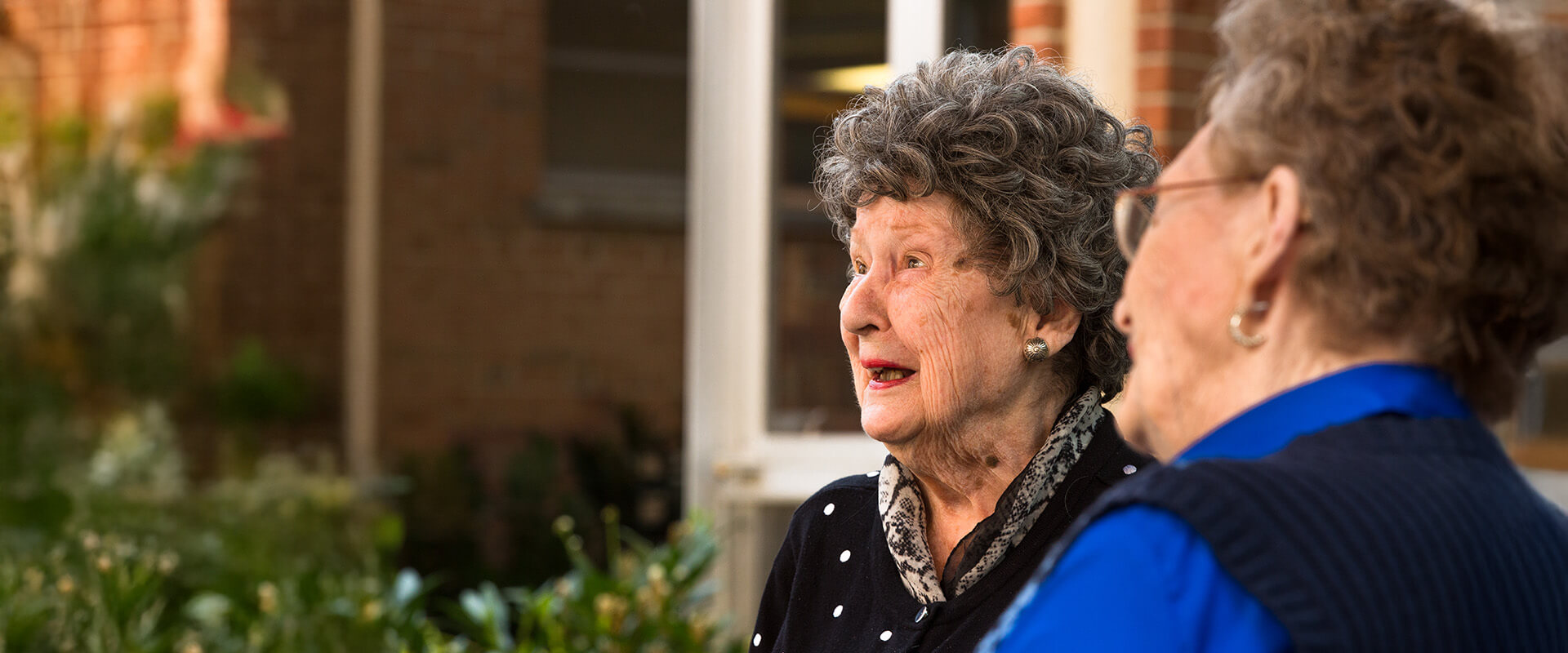 Two senior women sitting outdoors and talking