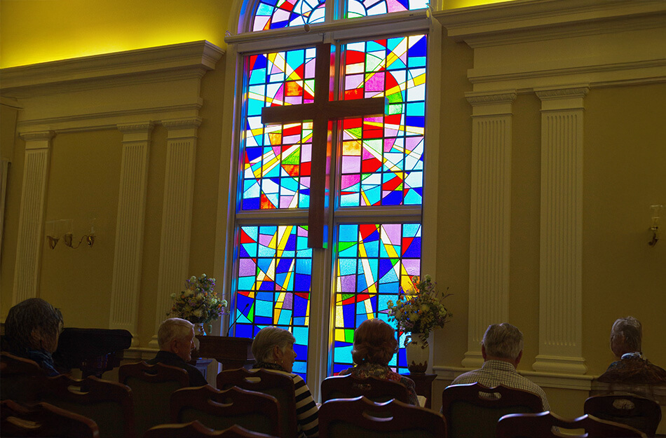 Seniors sitting in church near large stain glass