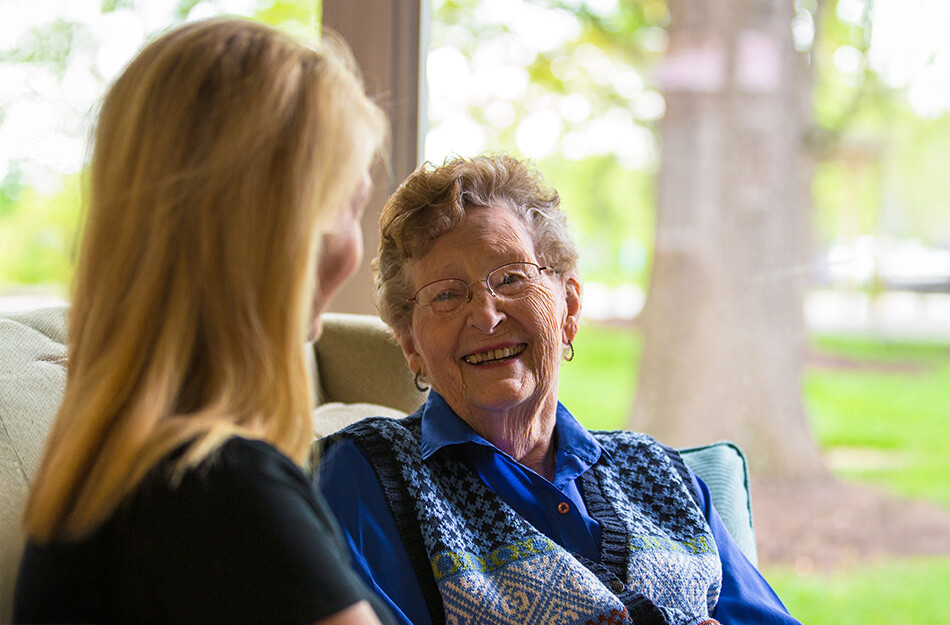 Senior woman and adult daughter sit on couch together