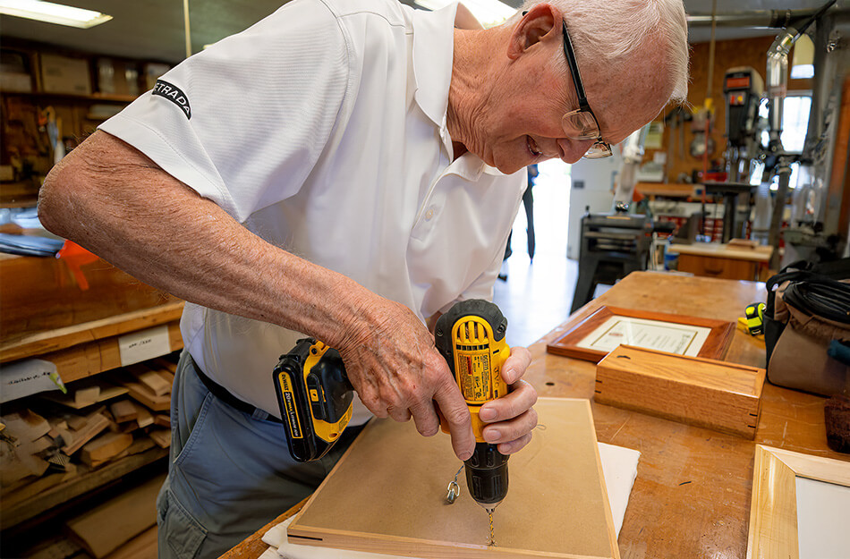 Senior man using a drill in a wood working shop