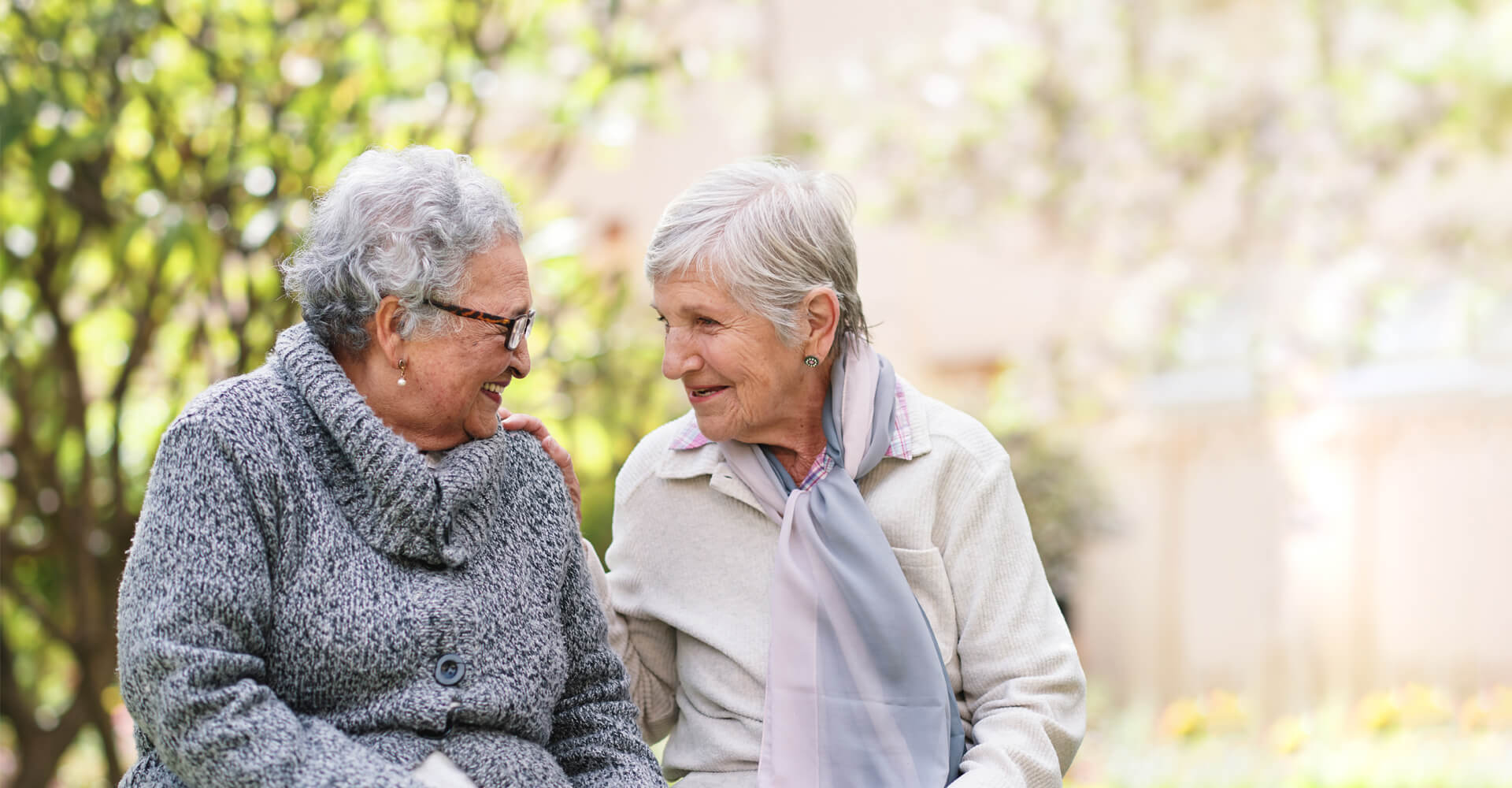 Close senior friends smiling at each other.