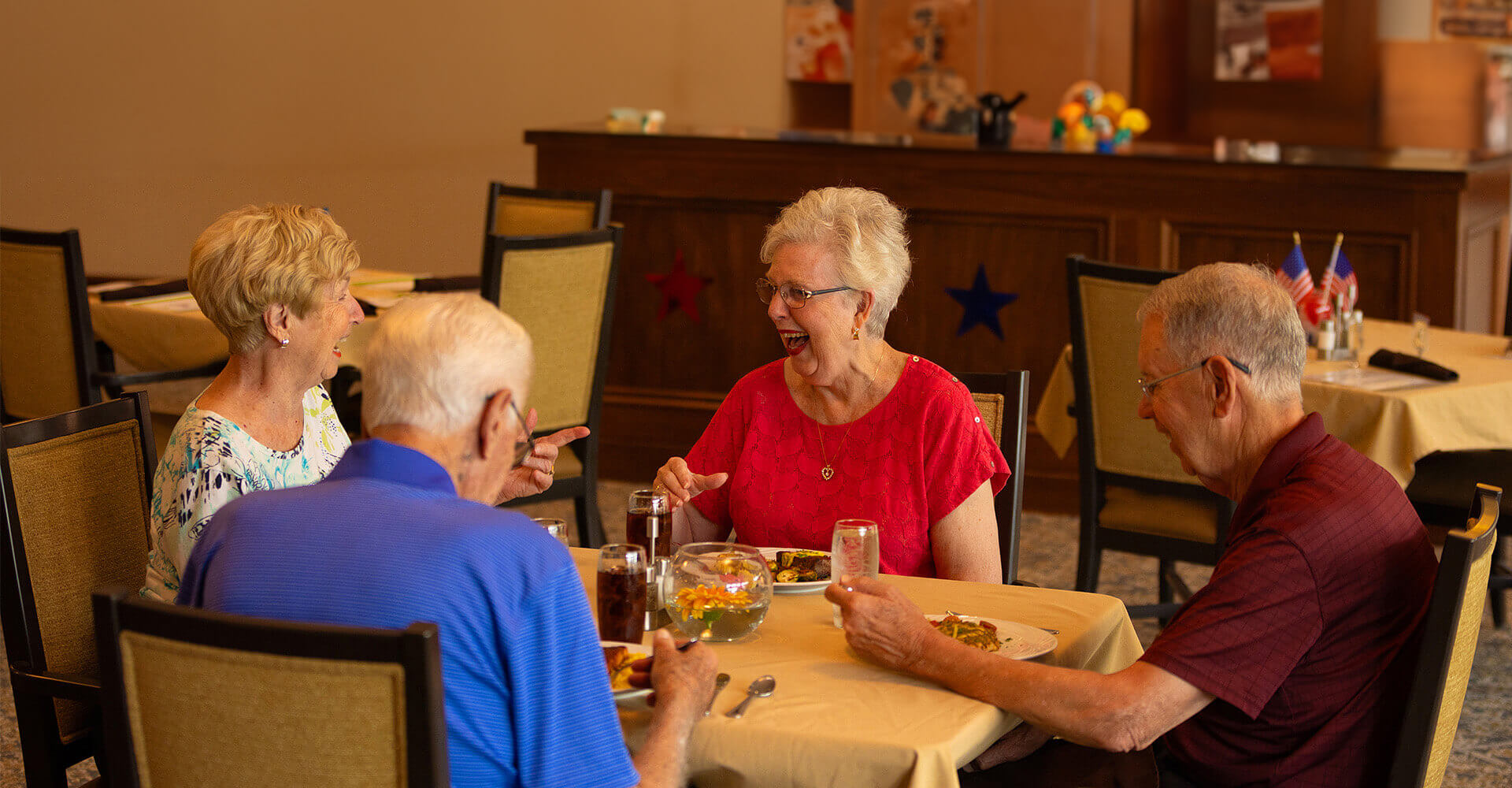 Friends laughing at dinner around a table.