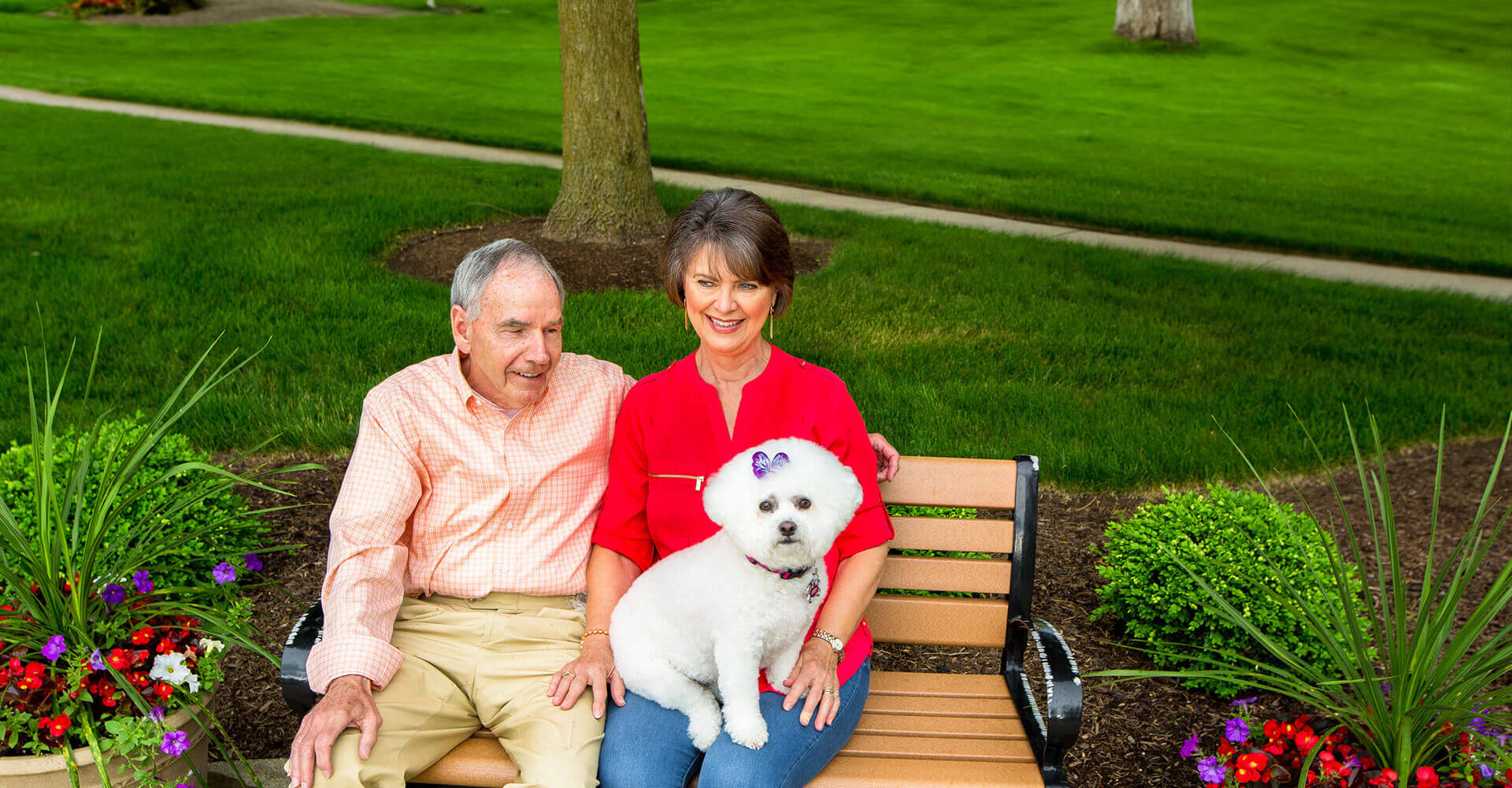 Senior couple sitting with their dog outside on a bench.