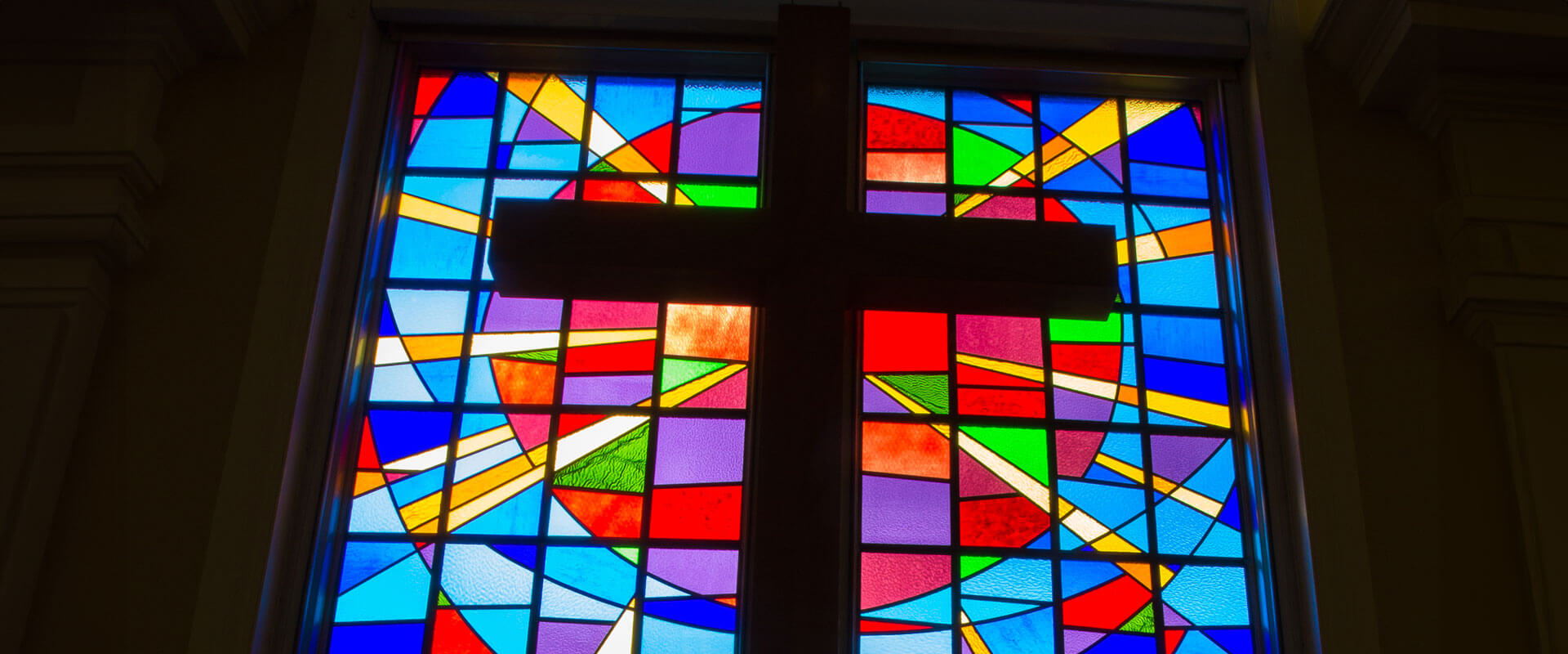 stained glass window with cross in front.