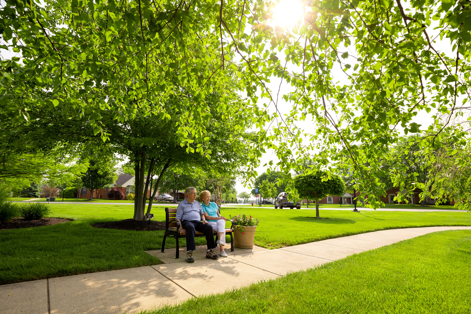 Elderly couple sits outside in the sunlight on a bench at the Christian Village at Mason.