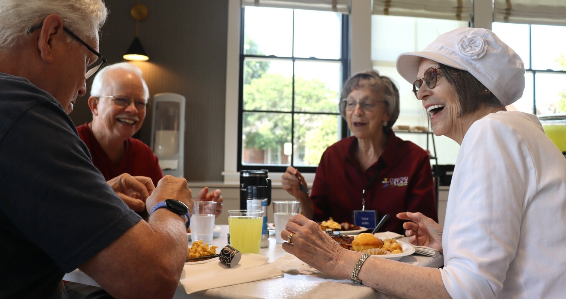 Residents at The Christian Village at Mason sit around a table, enjoying a barbeque lunch at the newly opened Bistro at Sunrise Vista.