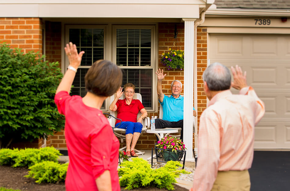 Senior residents at the Christian Village at Mason sit outside their independent living Garden Home and wave to some of their neighbors passing by.
